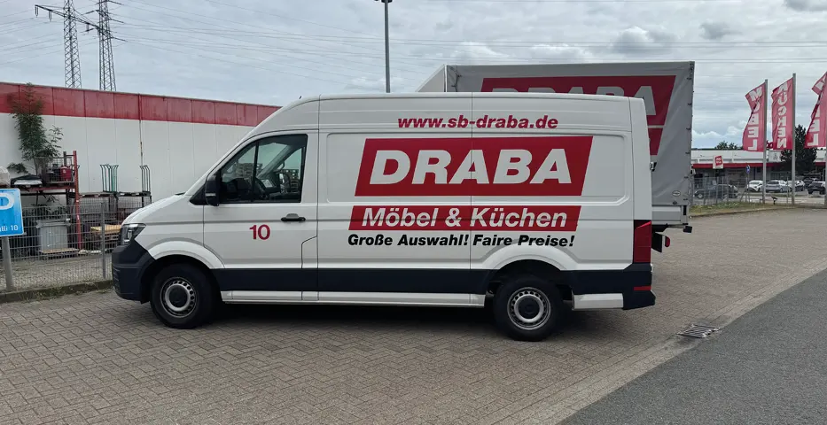 Weißer DRABA Lieferwagen mit Aufschrift Möbel und Küchen vor Möbelhalle